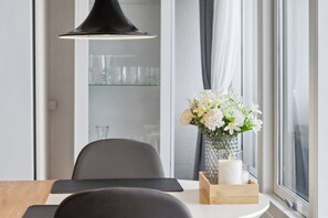 Un espace repas comprenant une table, des chaises, un vase avec des fleurs, des bougies et un luminaire suspendu.