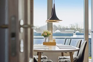 Une table à manger avec des chaises, un vase de fleurs, une bougie et une suspension.