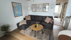 A modern living room with a sectional sofa, a coffee table, and a map on the wall. - Cosy small holiday apartment for 4 persons (Tranekær)