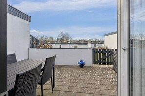 A patio with a table and chairs, a blue pot, and a gate.