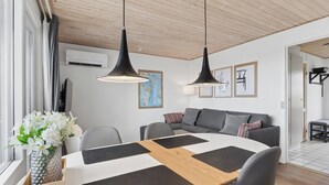 A modern living room with a dining table, grey sofa, and pendant lights. - Cosy small holiday apartment for 4 persons (Tranekær)