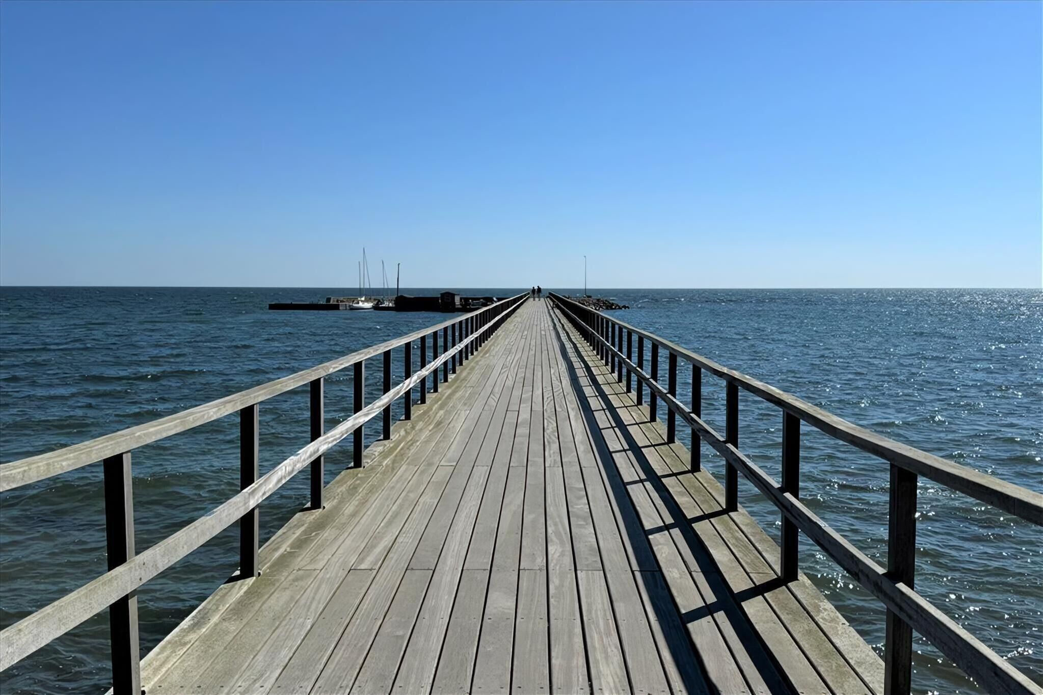 Een houten steiger die zich uitstrekt over kalm water, met een heldere lucht erboven.
