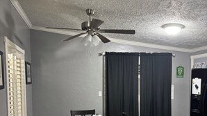 A dining area with a table, chairs, a ceiling fan, and a refrigerator.
