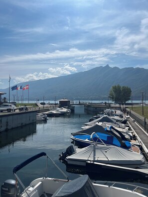 A marina with boats docked, a bridge, and mountains in the background. - Nid du Lac - Cosy & modern lakeside studio with terrace (Aix-les-Bains)