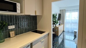 Una cocina moderna con microondas, un lavamanos y una encimera. Se ve un comedor con una mesa y sillas.