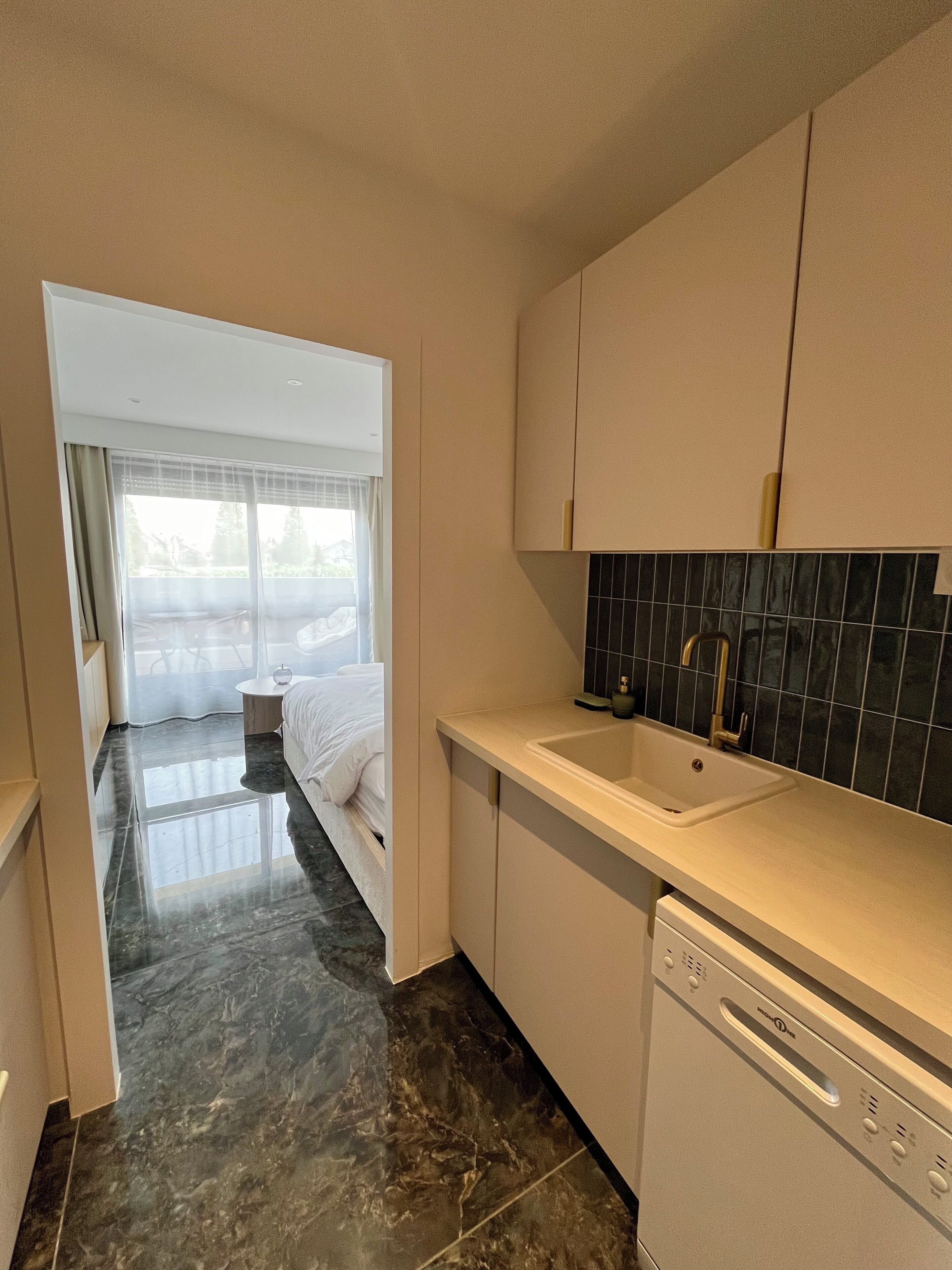 A modern kitchen with a white countertop, black backsplash, and a built-in dishwasher.