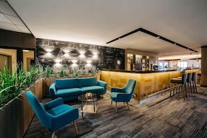 Een moderne bar met een houten toonbank, barstoelen en een zithoek met een bank en stoelen.