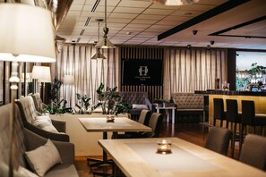 A hotel lobby with seating areas, a reception desk, and a large sign with the hotel name. - Novotel Olsztyn (Olsztyn)