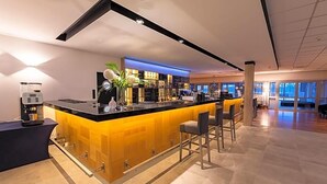 A modern bar area with a counter, stools, and a coffee machine. - Novotel Olsztyn (Olsztyn)