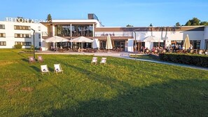 A hotel with outdoor seating, a grassy lawn, and a modern building facade. - Novotel Olsztyn (Olsztyn)