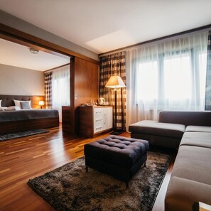 A modern hotel room with a bed, a sofa, a small ottoman, a desk, and a lamp. - Novotel Olsztyn (Olsztyn)