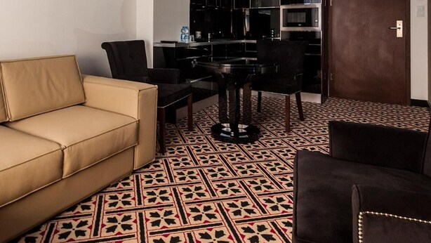 Un salon moderne comprenant un canapé, des fauteuils, une table à manger et un sol à motifs.