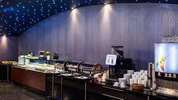 A buffet area with a curved wall, ceiling lights, and a coffee machine.