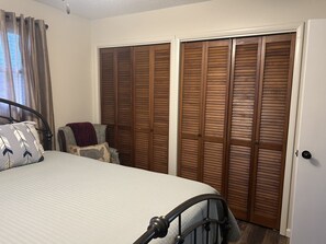 A bedroom with a bed, a chair, and a set of wooden sliding doors.
