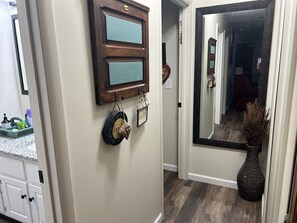 A hallway with a wooden door, a mirror, and a vase.