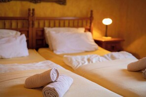 Ein Hotelzimmer mit zwei Betten, jeweils mit weißer Bettwäsche und aufgerollten Handtüchern.