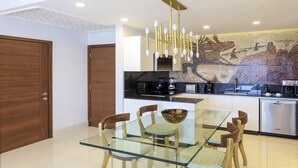 A modern kitchen with a glass dining table, wooden chairs, and a mosaic wall. - Modern 1-bedroom hotel suites in charming Cancun  Mexico (Cabo San Lucas)