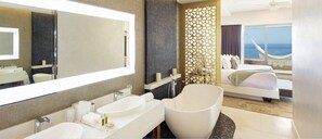 Une chambre d’hôtel moderne dotée d’une grande salle de bain, d’un lit avec vue sur l’océan et d’un balcon agrémenté d’un hamac.