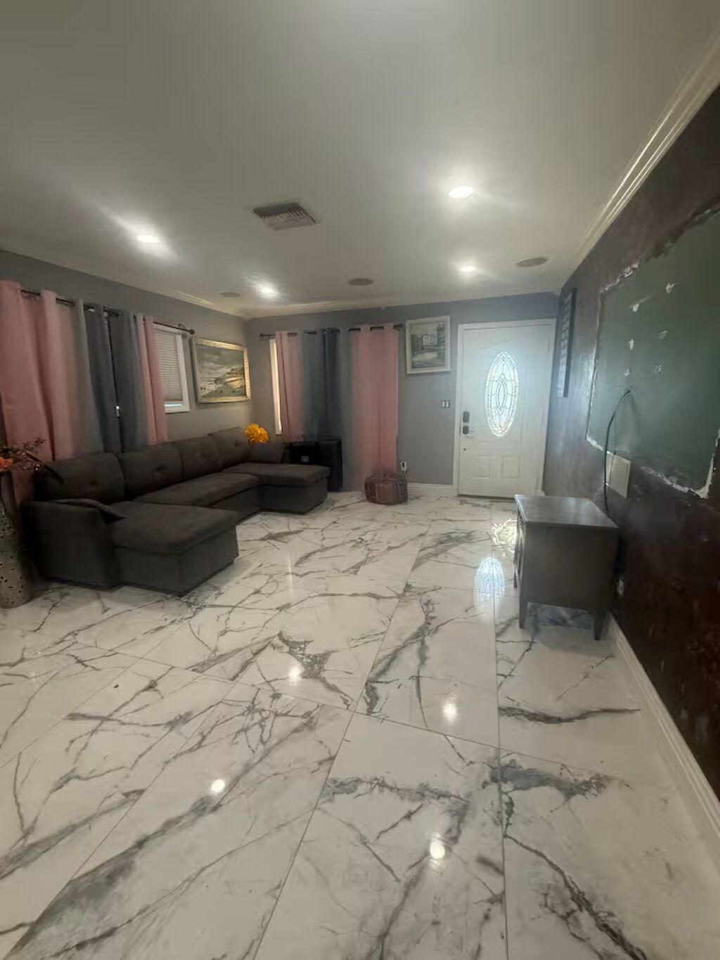 A living room with a sectional sofa, a small table, and a door with a decorative glass panel.