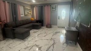 A living room with a sectional sofa, a small table, and a door with a decorative glass panel. - 3-bedroom house in enchanting in  LA with AC  fitness area and swimming pool (Los Angeles)