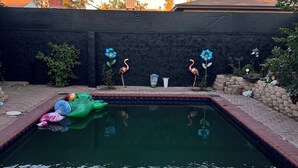 A swimming pool with inflatable toys, a brick wall, and decorative flowers. - 3-bedroom house in enchanting in  LA with AC  fitness area and swimming pool (Los Angeles)