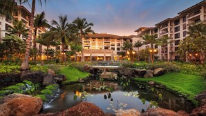 A resort with a central water feature, surrounded by lush greenery and palm trees.