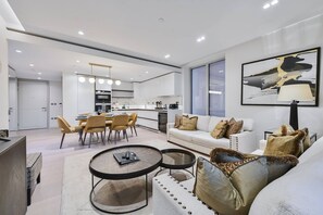 A modern living room with a sofa, coffee table, and dining area. - Spacious 3-bedroom Apartment in Central London (London)