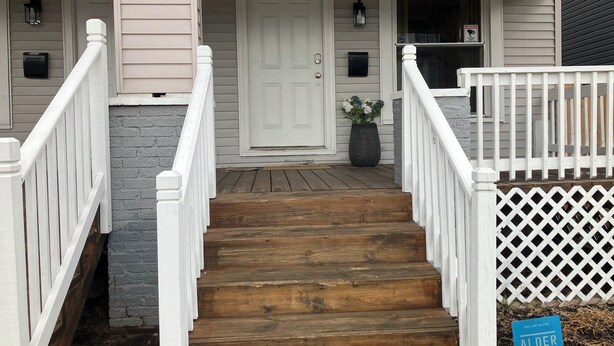 A wooden staircase leading to a white door with a mailbox and a potted plant beside it. - Bold 1922 Designer Home - 3BR Near German Village (Columbus)