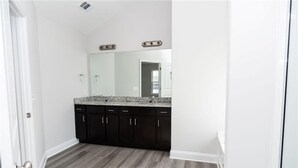 A bathroom with a large mirror, dark cabinets, and a granite countertop. - The Beautiful and Spacious Big House in Savannah GA (Savannah)