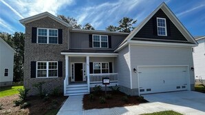 A two-story house with a garage, a front porch, and a well-maintained lawn. - The Beautiful and Spacious Big House in Savannah GA (Savannah)