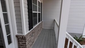 A covered porch with a brick base and white siding, leading to a door with glass panels. - The Beautiful and Spacious Big House in Savannah GA (Savannah)