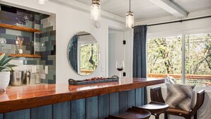 A bar area with a wooden counter, a round mirror, and a view of the outdoors.