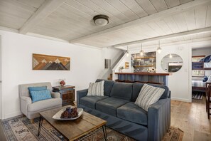 A living room with a sofa, a coffee table, and a painting on the wall. - Timberlake Chalet | FIFA Ready! (Lake Arrowhead)