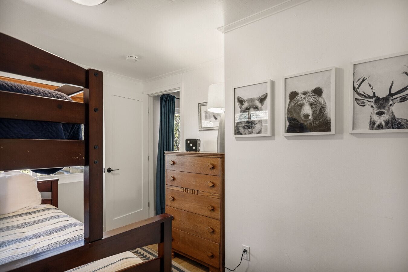 A bedroom with a bunk bed, a dresser, and wall art.