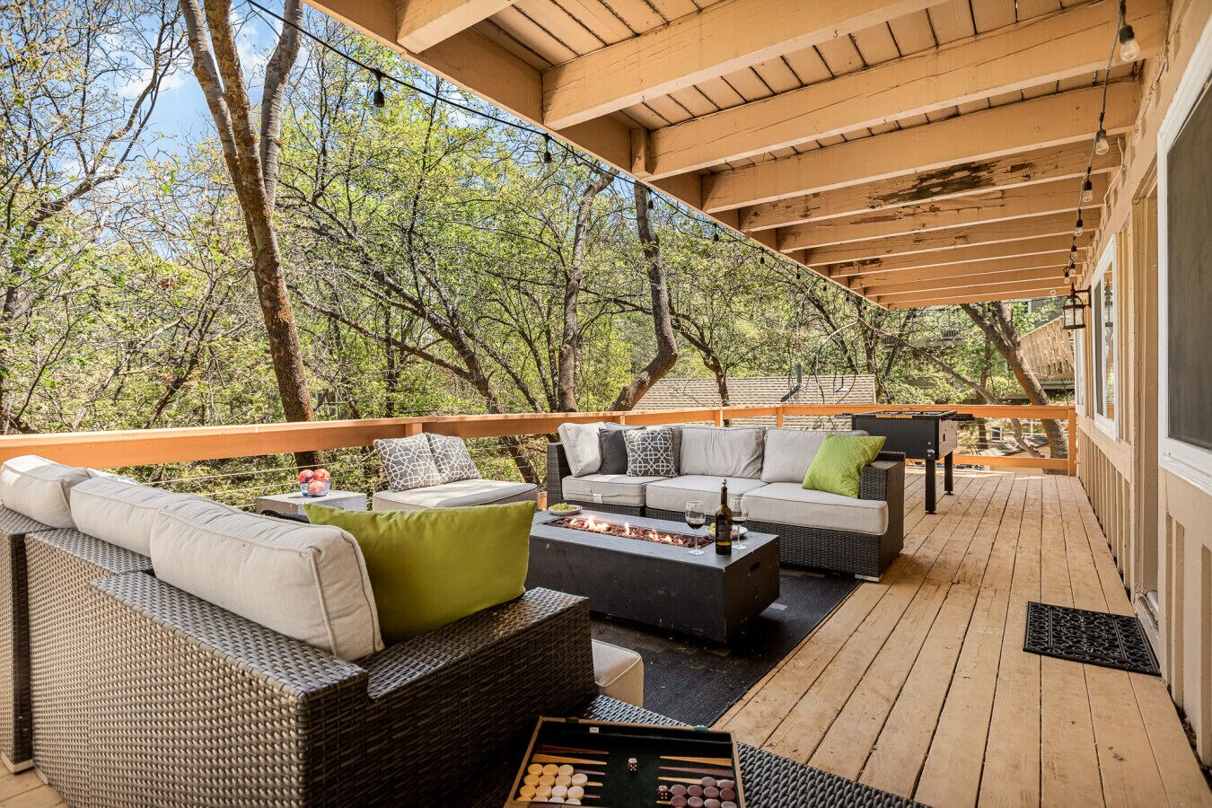 An outdoor deck with wicker furniture, a fire pit, and a view of trees.