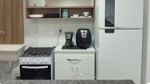 Een kleine keuken met een gasfornuis, koffiezetapparaat en een koelkast.