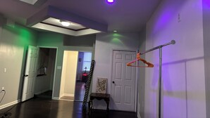 Un couloir avec un ventilateur de plafond, un porte-manteau et une porte donnant sur une autre pièce.