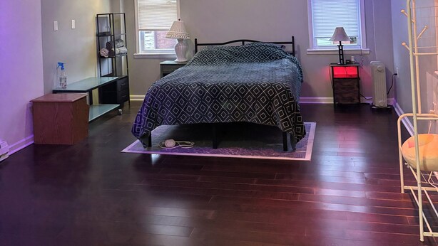 Une chambre à coucher avec un lit, un bureau, une chaise, un radiateur et une fenêtre.