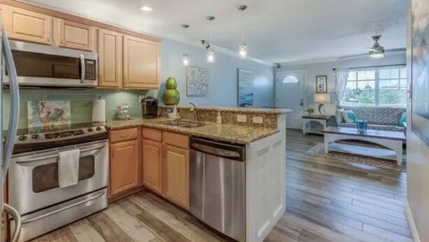 A kitchen with wooden cabinets, stainless steel appliances, and a granite countertop. - Pet Friendly, St. Pete Beach Condo w/AC, 1BR+Sofa Bed, Steps to Beach! (St. Pete Beach)