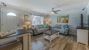 A spacious living room with a ceiling fan, a sofa set, a coffee table, and a dining area with a bench. - Pet Friendly, St. Pete Beach Condo w/AC, 1BR+Sofa Bed, Steps to Beach! (St. Pete Beach)