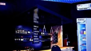 A restaurant with tables set for dining, a bar area, and a wall with illuminated signs. - Premium HOTEL (Douala)