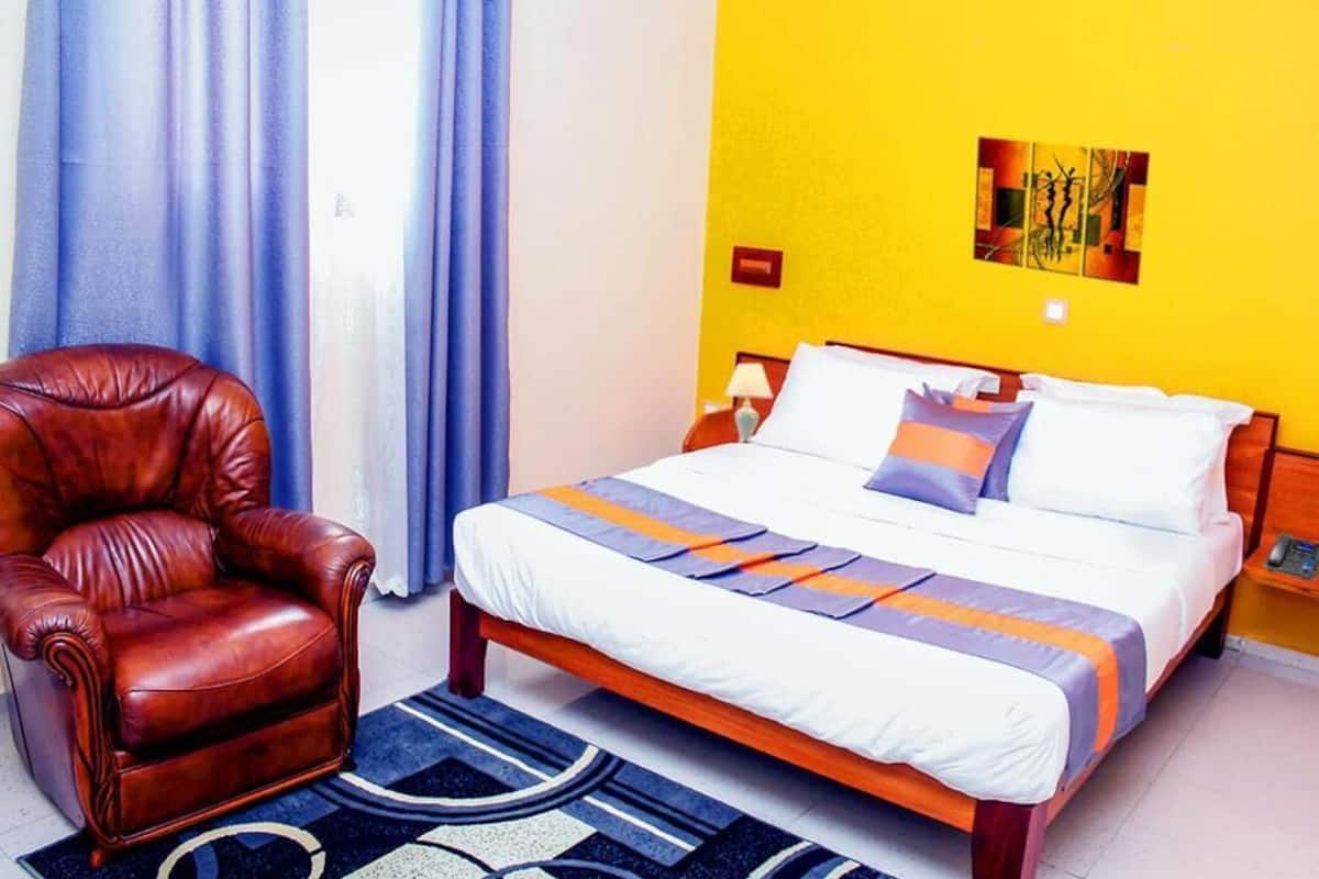 Una habitación de hotel con una cama, un sillón de cuero y una alfombra con estampado azul y blanco.