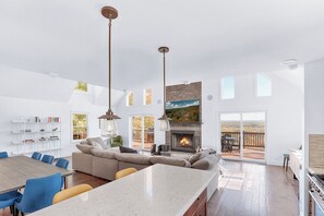 A spacious living room with a fireplace, a dining area with a large table, and a kitchen area. - Kingston Ridge Chalet - Hot Tub & Pool (Kingston)