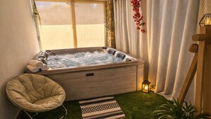 Une salle de bain moderne avec une baignoire en bois, un fauteuil rembourré et un petit tapis.