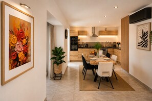 A modern kitchen with wooden cabinets, a central island, and a dining area with a table set for four.