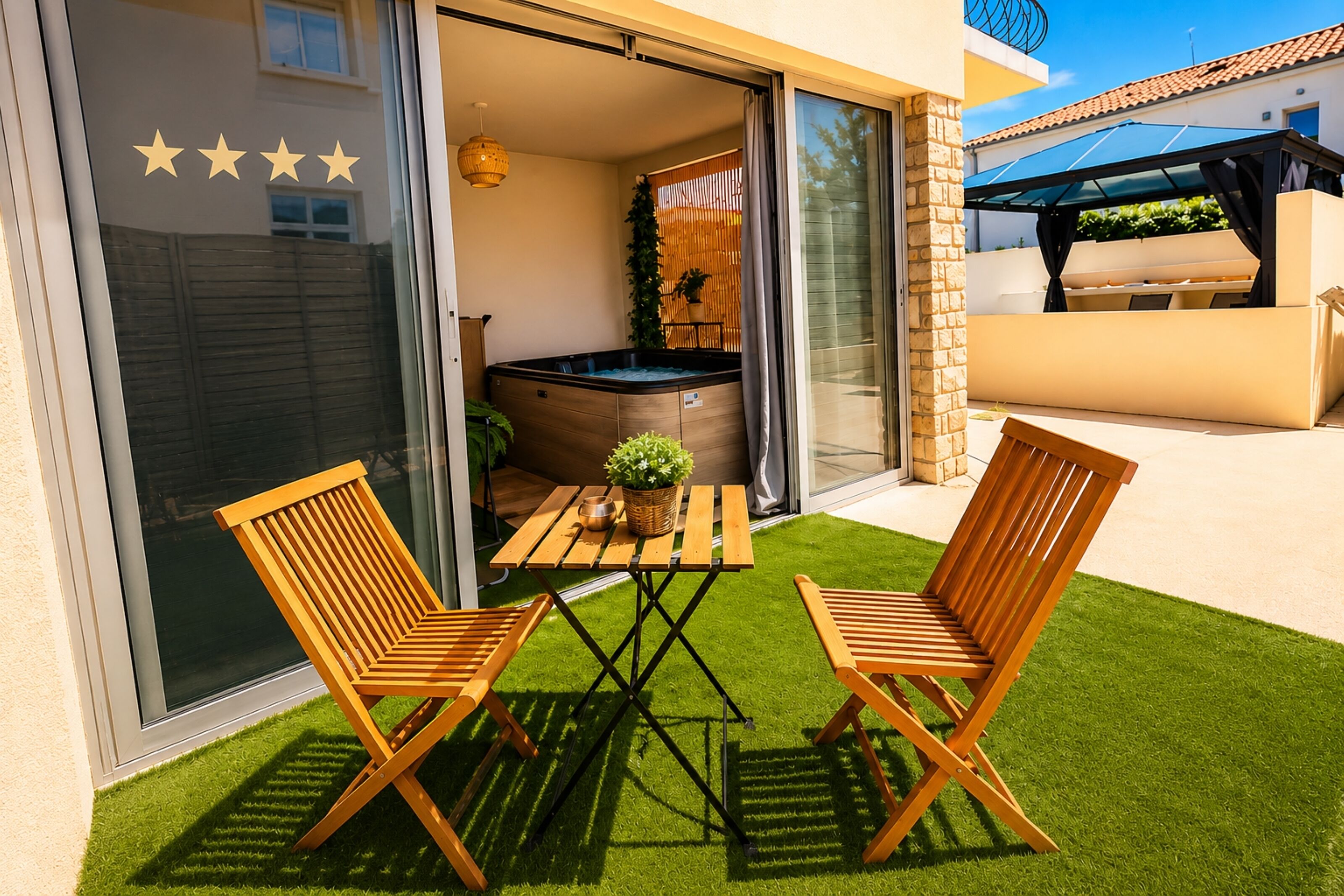 Une terrasse avec deux chaises en bois, une table et un jacuzzi.
