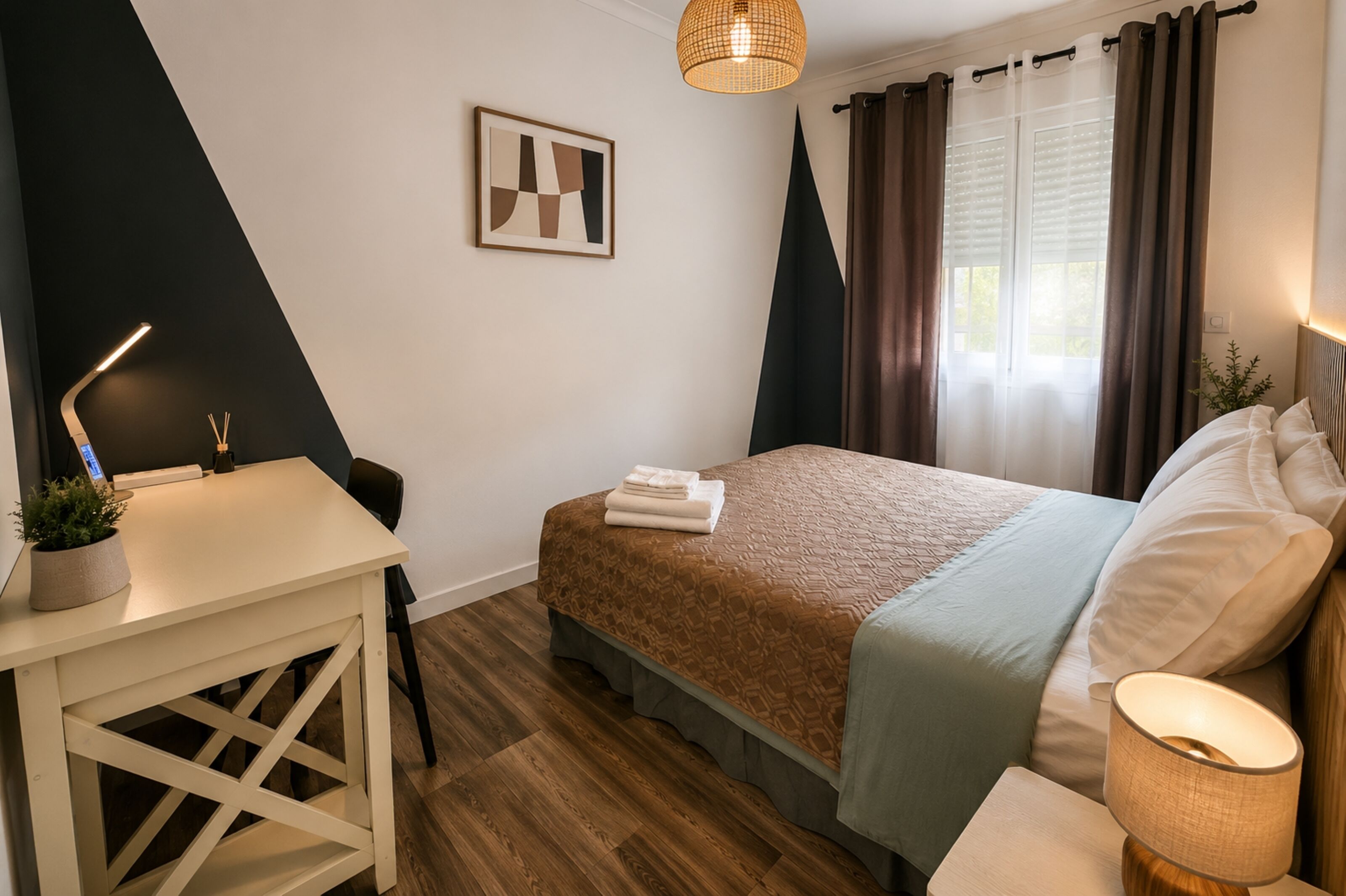 Un dormitorio con cama, mesita de noche, lámpara y un cuadro colgado en la pared.