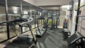 Een sportschool met loopbanden, krachtapparaten en een rek met gewichten.