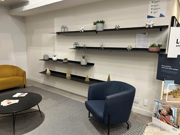 A modern hotel lobby with a reception desk, a blue armchair, a yellow sofa, and decorative shelves with plants and geometric ornaments. - TOP Stay Inn hotel 3 min Av Paulista (São Paulo)