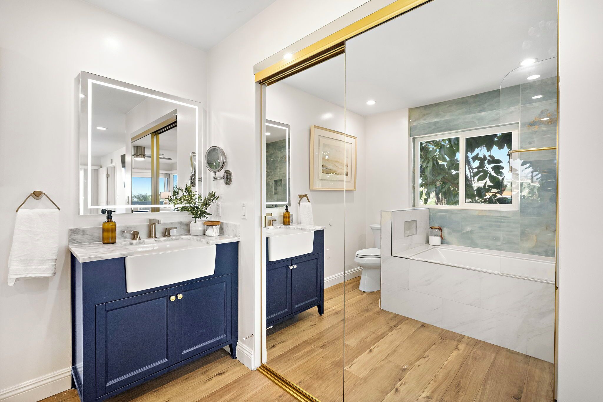 A modern bathroom with a large mirror, two sinks, and a toilet.